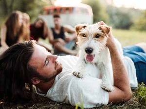 Small dog laying on owners stomach in the grass