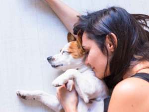 Woman cuddling with her dog on the ground